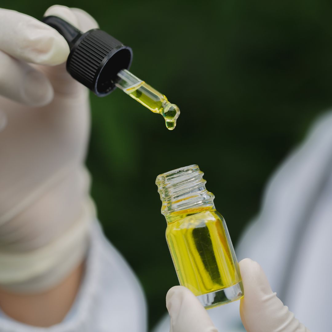 Medical-Cannabis latex-gloved hands hold a bottle of cannabis oil and a dropper